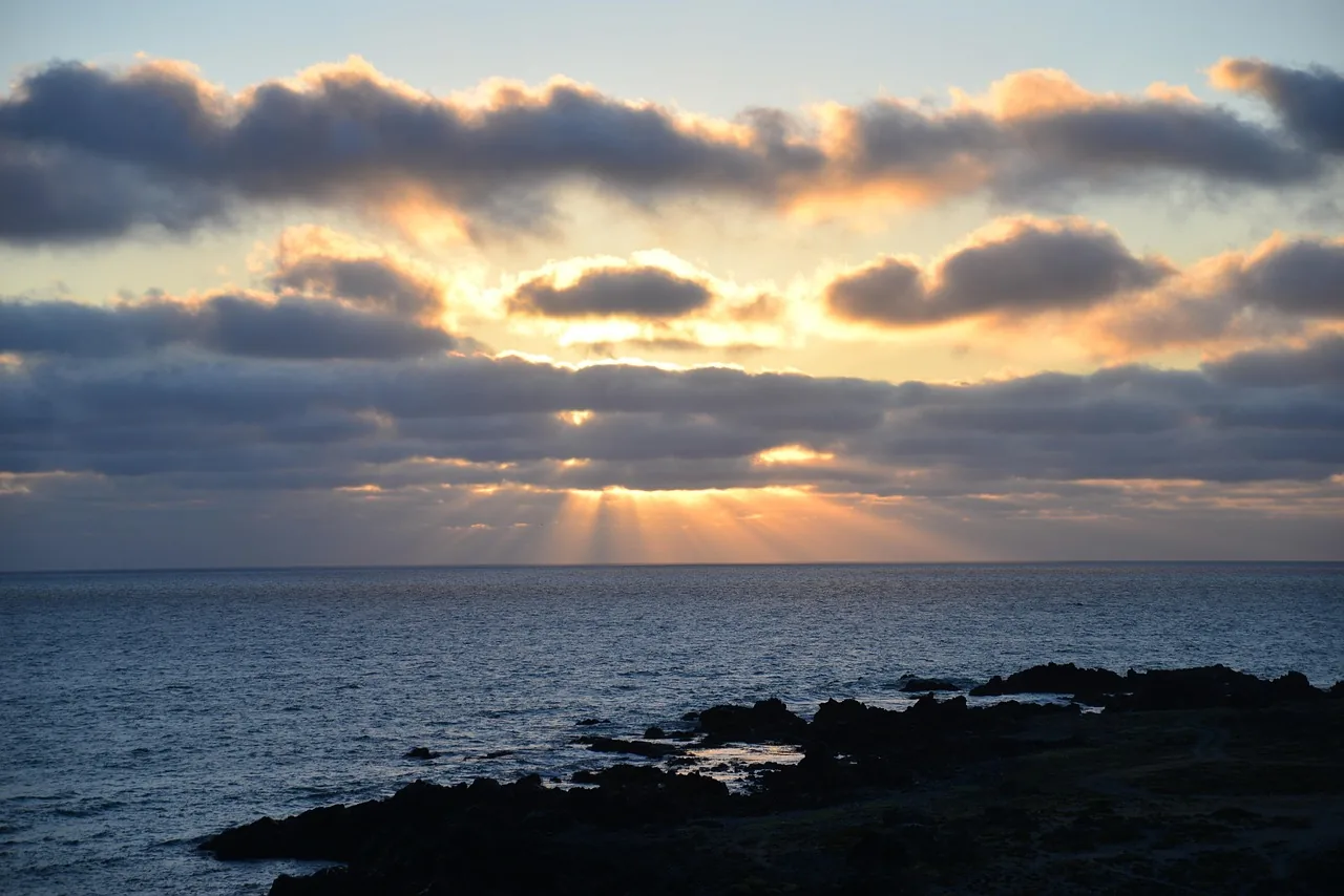 Sonnenstrahlen brechen durch dunkle Wolken über dem Meer